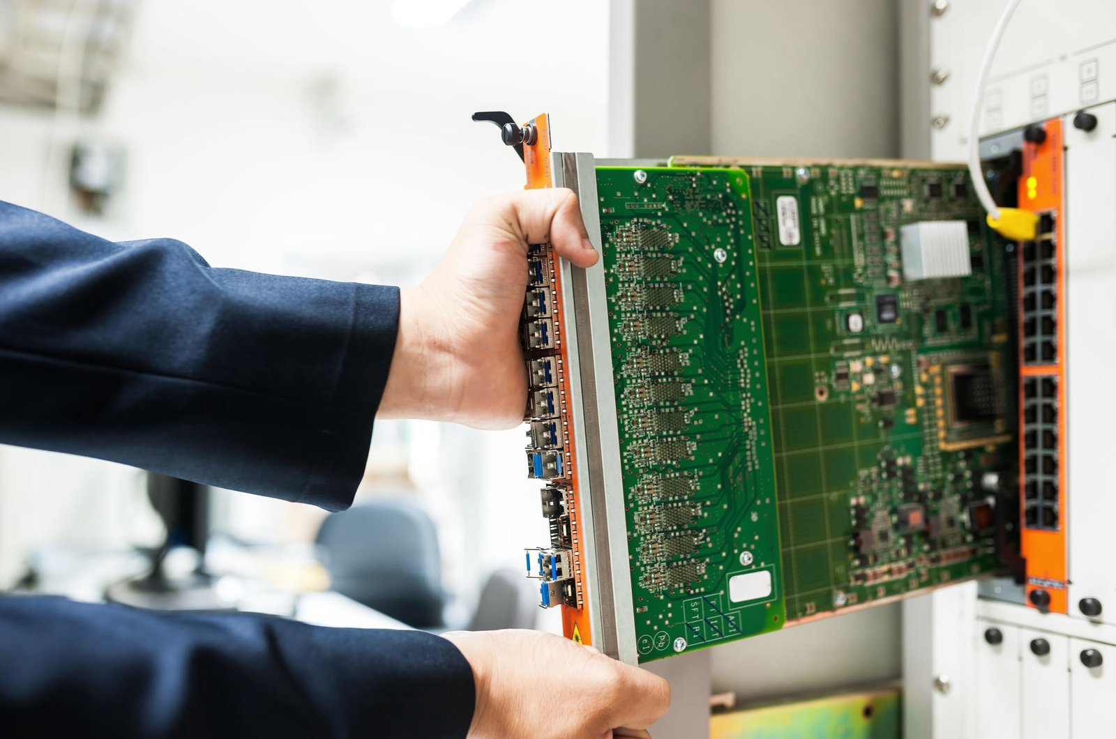 Hands seating a network line card into a chassis